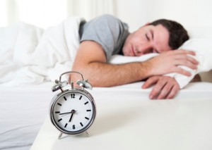 Man in bed next to alarm clock